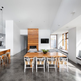 This is an example of a mid-sized contemporary open plan dining in Melbourne with white walls, concrete floors, grey floor, a standard fireplace and a wood fireplace surround.