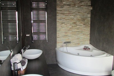 Ispirazione per un'ampia stanza da bagno con doccia minimalista con ante marroni, vasca idromassaggio, WC sospeso, piastrelle nere, piastrelle in gres porcellanato, pareti nere, pavimento in gres porcellanato, lavabo a bacinella, top in legno, pavimento nero, doccia a filo pavimento e porta doccia a battente