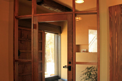 Example of a large mountain style marble floor, black floor and exposed beam entryway design in Other with beige walls and a dark wood front door