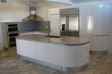 Example of a mid-sized l-shaped ceramic tile eat-in kitchen design in San Diego with an undermount sink, flat-panel cabinets, white cabinets, granite countertops, gray backsplash, stone slab backsplash and stainless steel appliances
