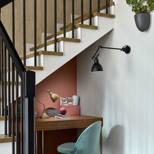 Idéer för att renovera ett litet funkis hemmabibliotek, med ett inbyggt skrivbord, mellanmörkt trägolv och rosa väggar