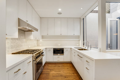 Modelo de cocina contemporánea de tamaño medio con armarios con paneles lisos, puertas de armario blancas, encimera de cuarcita, salpicadero blanco, una isla y encimeras blancas