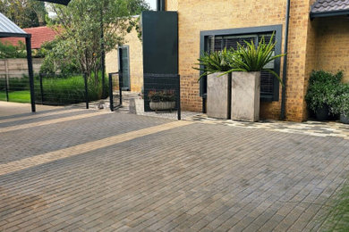 Design ideas for a large contemporary full sun front yard concrete paver and metal fence landscaping in Other.