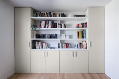 Inspiration pour un salon minimaliste de taille moyenne avec une bibliothèque ou un coin lecture, un mur blanc, parquet clair, aucune cheminée et aucun téléviseur.
