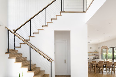 Imagen de escalera en U contemporánea grande con escalones de madera, contrahuellas de madera y barandilla de cable