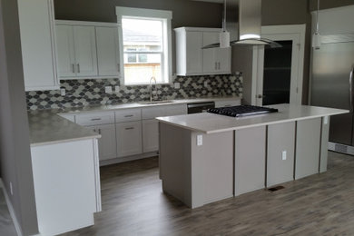 Inspiration for a mid-sized craftsman l-shaped vinyl floor and gray floor eat-in kitchen remodel in Seattle with a single-bowl sink, shaker cabinets, white cabinets, solid surface countertops, multicolored backsplash, porcelain backsplash, stainless steel appliances, an island and white countertops