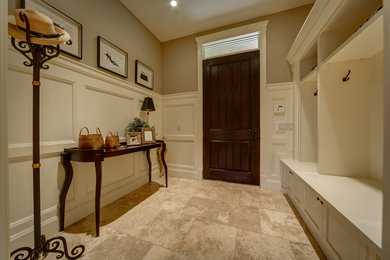 Design ideas for a mid-sized transitional mudroom in Calgary with brown walls, limestone floors, a single front door and a dark wood front door.