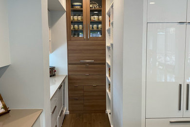 Inspiration for a mid-sized contemporary u-shaped kitchen pantry remodel in Seattle with flat-panel cabinets, white cabinets, quartz countertops, paneled appliances and beige countertops