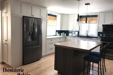 Mid-sized elegant l-shaped light wood floor open concept kitchen photo in Montreal with a double-bowl sink, shaker cabinets, white cabinets, laminate countertops, blue backsplash, ceramic backsplash, black appliances, an island and gray countertops