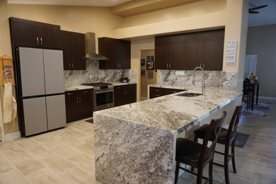 Eat-in kitchen - large porcelain tile and beige floor eat-in kitchen idea in Las Vegas with an undermount sink, flat-panel cabinets, dark wood cabinets, granite countertops, white backsplash, granite backsplash and white countertops