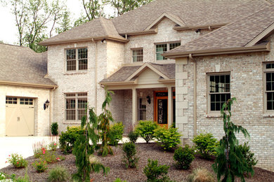 Example of a large classic beige two-story brick gable roof design in Other