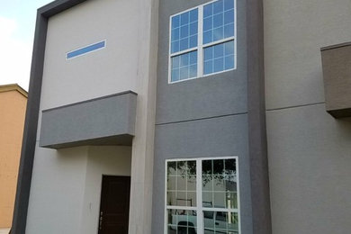 Example of a mid-sized minimalist gray two-story stucco exterior home design in Austin with a green roof