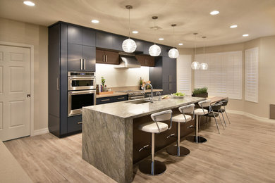 Inspiration for a large transitional l-shaped separate kitchen in Phoenix with an undermount sink, flat-panel cabinets, blue cabinets, white splashback, stainless steel appliances, light hardwood floors, with island and grey benchtop.