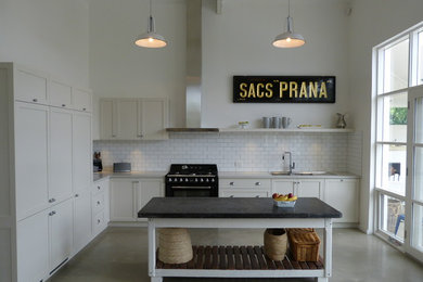 This is an example of a mid-sized traditional l-shaped eat-in kitchen in Adelaide with a double-bowl sink, shaker cabinets, white cabinets, quartz benchtops, white splashback, ceramic splashback, black appliances, concrete floors, with island and grey floor.