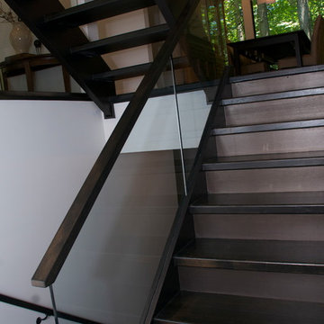 Open rise stair with glass panels and hand forged iron rails