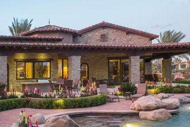 Large island style beige one-story stone exterior home photo in Other with a shingle roof
