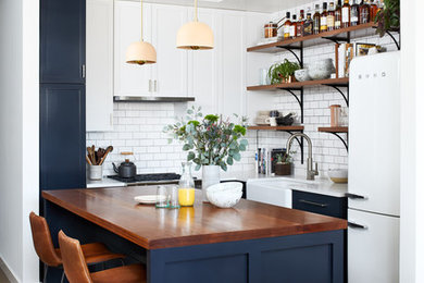 Example of a small eclectic l-shaped porcelain tile and brown floor open concept kitchen design in DC Metro with a farmhouse sink, shaker cabinets, blue cabinets, quartz countertops, white backsplash, ceramic backsplash, white appliances and an island