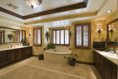 This is an example of a large mediterranean master bathroom in Tampa with raised-panel cabinets, dark wood cabinets, an undermount tub, beige walls, ceramic floors, an undermount sink, beige floor and beige benchtops.
