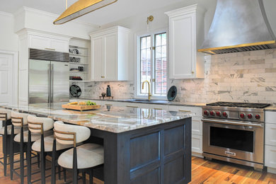 Example of a large transitional brown floor and medium tone wood floor enclosed kitchen design with an undermount sink, recessed-panel cabinets, quartzite countertops, white backsplash, marble backsplash, stainless steel appliances, an island, white cabinets and multicolored countertops