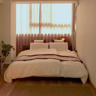 Esempio di una camera matrimoniale etnica di medie dimensioni con pareti bianche, pavimento in vinile e pavimento marrone