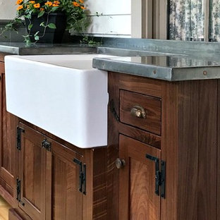 Inspiration for a medium sized country utility room in Philadelphia with a belfast sink, shaker cabinets, dark wood cabinets, zinc worktops, beige walls, light hardwood flooring, brown floors and grey worktops.