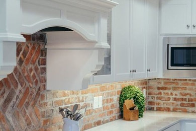 Open concept kitchen - huge l-shaped light wood floor and brown floor open concept kitchen idea in Other with recessed-panel cabinets, brick backsplash, stainless steel appliances and an island