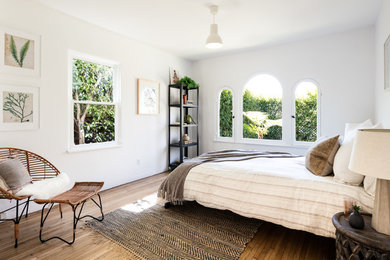 This is an example of a mediterranean bedroom in Los Angeles with white walls, medium hardwood floors and brown floor.