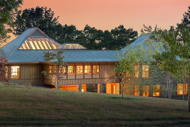 Photo of a large contemporary three-storey green house exterior in Other with concrete fiberboard siding, a hip roof and a metal roof.