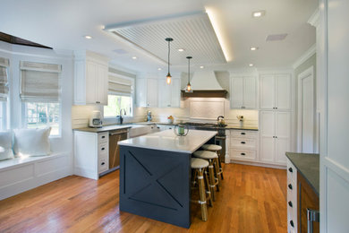 This is an example of a mid-sized transitional l-shaped kitchen in Other with a farmhouse sink, beaded inset cabinets, white cabinets, soapstone benchtops, white splashback, panelled appliances, light hardwood floors, with island, brown floor, black benchtop and timber.