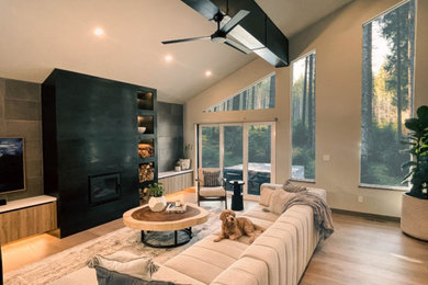 Large trendy open concept light wood floor, brown floor and exposed beam family room photo in Sacramento with gray walls, a wood stove, a metal fireplace and a wall-mounted tv