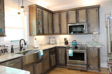 Inspiration for a large coastal u-shaped medium tone wood floor and brown floor kitchen remodel in Miami with a farmhouse sink, shaker cabinets, medium tone wood cabinets, granite countertops, stainless steel appliances and no island