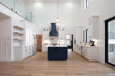 Example of a large minimalist kitchen design in Charleston with a farmhouse sink, shaker cabinets, white cabinets, stainless steel appliances and an island