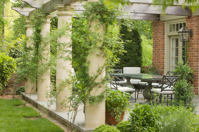 Elegant backyard stone patio photo in Richmond with a pergola