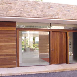 ロンドンの大きいコンテンポラリースタイルのおしゃれな地下室 (半地下 (ドアあり)、ベージュの壁、ライムストーンの床、コーナー設置型暖炉、漆喰の暖炉まわり、ベージュの床) の写真