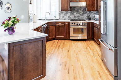 Mid-sized arts and crafts u-shaped light wood floor and yellow floor eat-in kitchen photo in Portland with an undermount sink, flat-panel cabinets, dark wood cabinets, quartz countertops, multicolored backsplash, stone tile backsplash, stainless steel appliances, a peninsula and white countertops