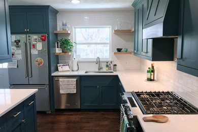 Example of a mid-sized transitional l-shaped dark wood floor and brown floor eat-in kitchen design in Dallas with an undermount sink, shaker cabinets, blue cabinets, quartz countertops, white backsplash, subway tile backsplash, stainless steel appliances, an island and white countertops