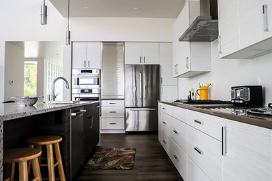 Mid-sized trendy galley dark wood floor eat-in kitchen photo in Other with stainless steel appliances, an island, an undermount sink, flat-panel cabinets, white cabinets, solid surface countertops, white backsplash and subway tile backsplash