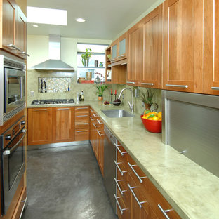 Mittelgroße Asiatische Küche in L-Form mit Vorratsschrank, Einbauwaschbecken, Schrankfronten mit vertiefter Füllung, hellbraunen Holzschränken, Betonarbeitsplatte, Küchenrückwand in Grün, Küchengeräten aus Edelstahl und Betonboden in San Francisco