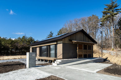 Foto de fachada de casa marrón de una planta con revestimiento de madera y tejado a dos aguas