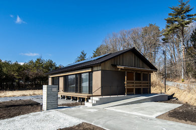 Foto della villa marrone a un piano con rivestimento in legno e tetto a capanna