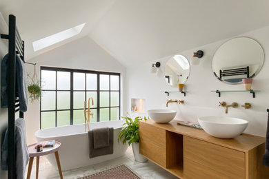 Photo of a large scandinavian kids bathroom in Other with flat-panel cabinets, medium wood cabinets, a freestanding tub, a wall-mount toilet, white tile, ceramic tile, white walls, ceramic floors, wood benchtops, grey floor, a double vanity and a floating vanity.