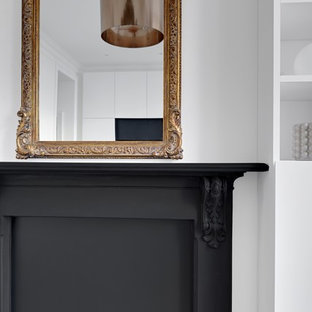 Immagine di un piccolo soggiorno vittoriano aperto con libreria, pareti bianche, parquet chiaro, nessun camino, cornice del camino in metallo, parete attrezzata e pavimento marrone