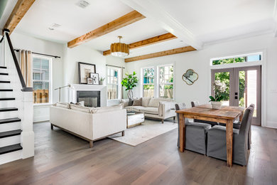 Living room - open concept brown floor and exposed beam living room idea in Jacksonville with white walls, a standard fireplace, a wood fireplace surround and no tv