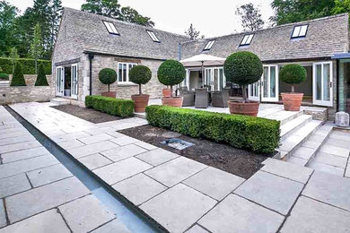 Large rural courtyard patio with a water feature and natural stone paving.