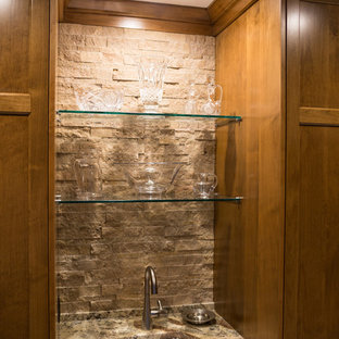 Photo of a large arts and crafts l-shaped kitchen pantry in Minneapolis with shaker cabinets, medium wood cabinets, granite benchtops, beige splashback, stone tile splashback, stainless steel appliances, limestone floors, with island and a single-bowl sink.