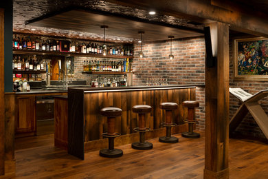 Immagine di una grande taverna boho chic interrata con angolo bar, pavimento in legno massello medio e nessun camino