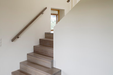 Imagen de escalera en L minimalista de tamaño medio con escalones de madera, contrahuellas de madera y barandilla de madera