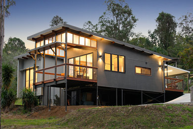 This is an example of a mid-sized modern one-storey black house exterior in Brisbane with concrete fiberboard siding, a flat roof and a metal roof.