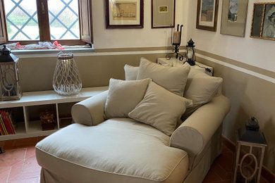 Esempio di un piccolo soggiorno stile marinaro chiuso con pareti marroni, pavimento in terracotta, camino bifacciale, cornice del camino in intonaco e pavimento marrone