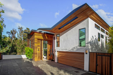 Large contemporary three-storey white house exterior in Los Angeles with wood siding and a metal roof.